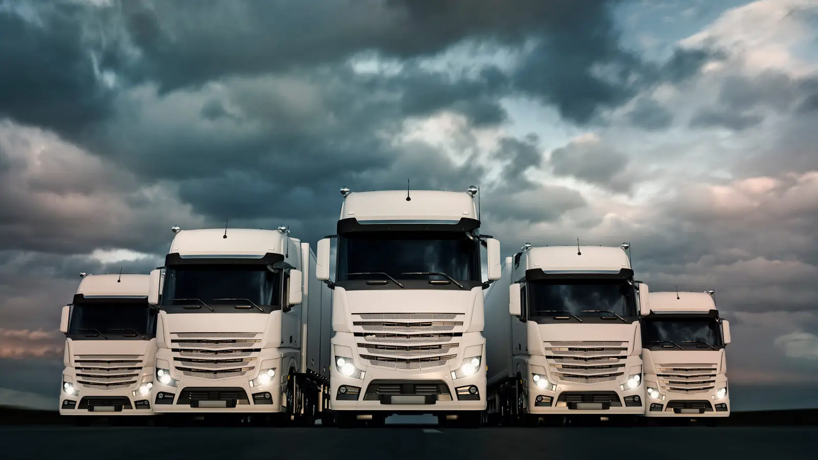 Fünf Lkw frontal unter bewölktem Himmel